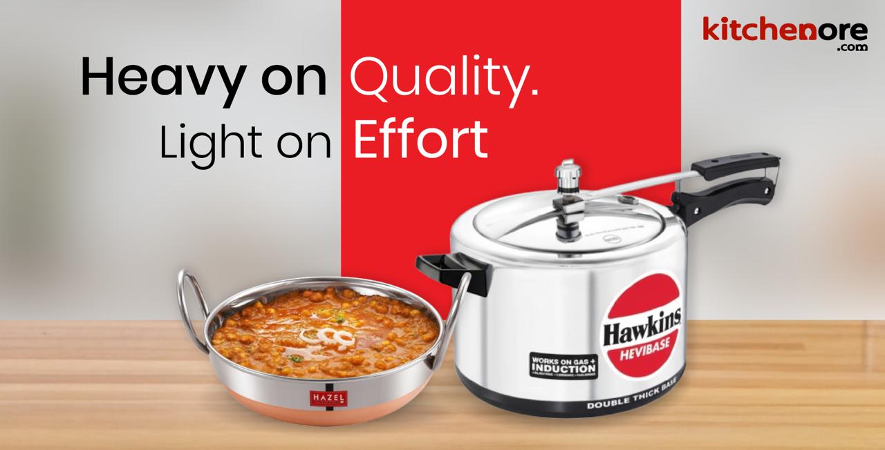 KitchenOre banner with Hawkins Hevibase pressure cooker and Hazel kadai filled with curry, tagline Heavy on Quality. Light on Effort